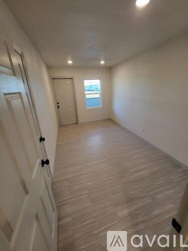 A room with wooden flooring and a window with a view of a building.
