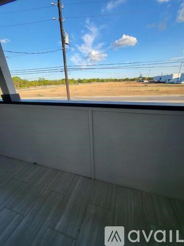 A view from inside a building looking out to a field with a utility pole.