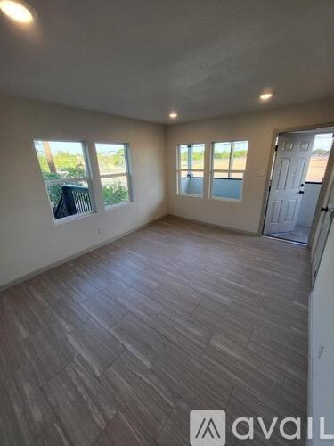 A room with wooden flooring and a door leading to a balcony.