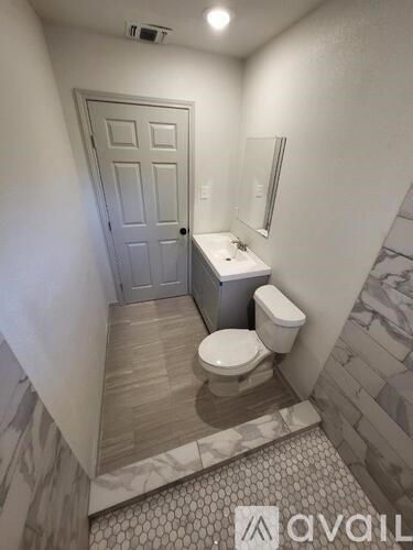 A bathroom with a toilet, sink, and mirror.