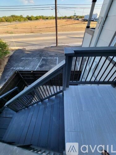 A staircase with a metal railing leading down to a parking lot.