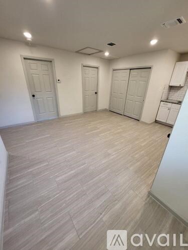 A room with wooden flooring and three white doors.
