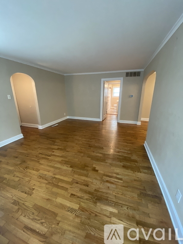 A room with wooden flooring and a doorway leading to another room.