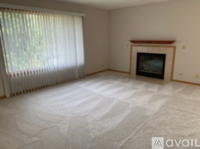 A living room with a fireplace and a window with blinds.