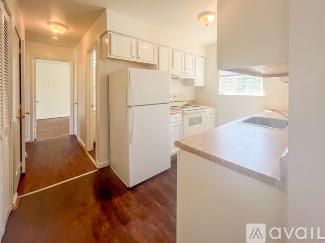A kitchen with white appliances and wooden floors.