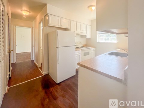 A kitchen with white appliances and wooden floors.