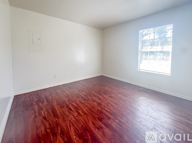 A room with wooden flooring and a window letting in natural light.
