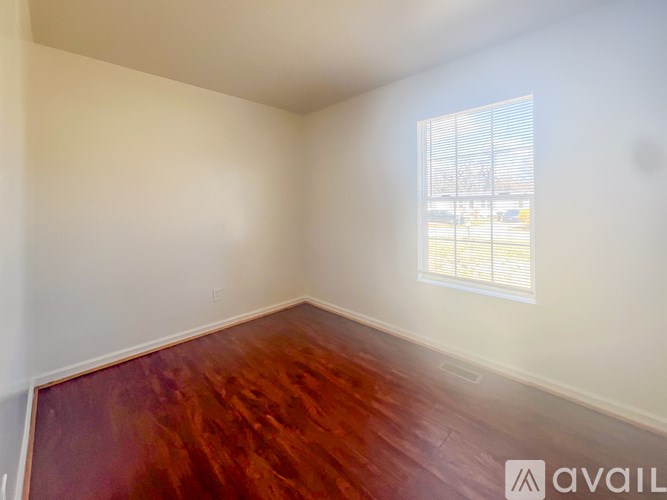 A room with wooden flooring and a window with blinds.
