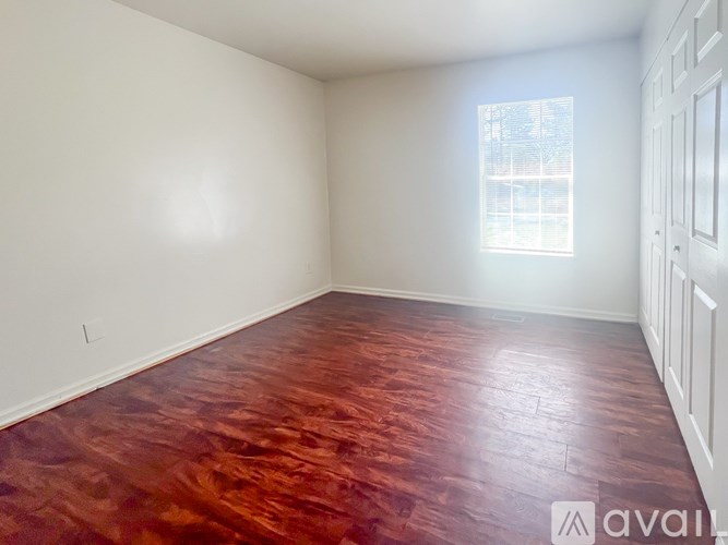 A room with wooden flooring and a window letting in light.