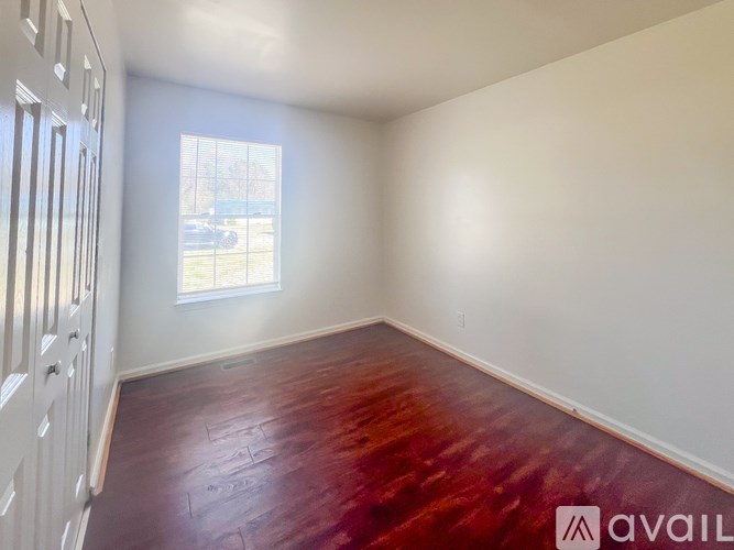 A room with a window and a wooden floor.