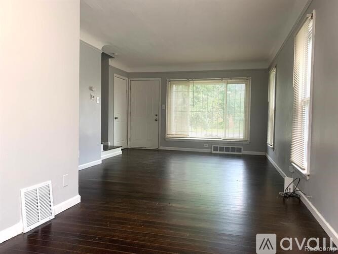 A room with wooden floors and a window with blinds.