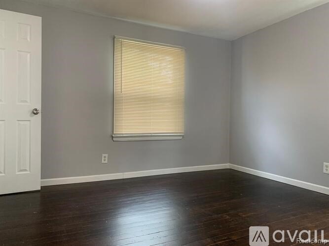 A room with wooden floors and a window with blinds.