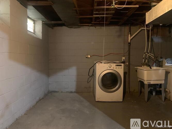 A dirty basement with a washing machine and a table.