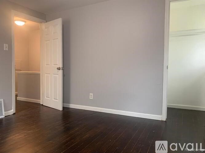 A room with a white door and a wooden floor.