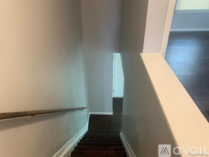 A hallway with a wooden floor and white walls.