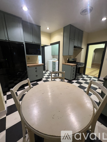 A kitchen with black and white checkered floor and a table in the middle.