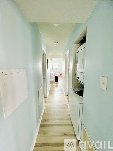 A long hallway with a white wall and a white door.