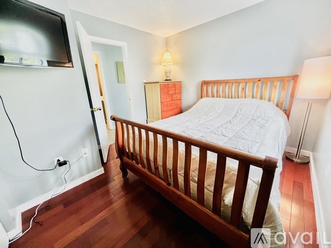 A bedroom with a bed, wooden nightstand, and a television.