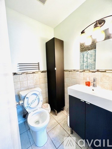 A white toilet sits next to a black cabinet in a bathroom.