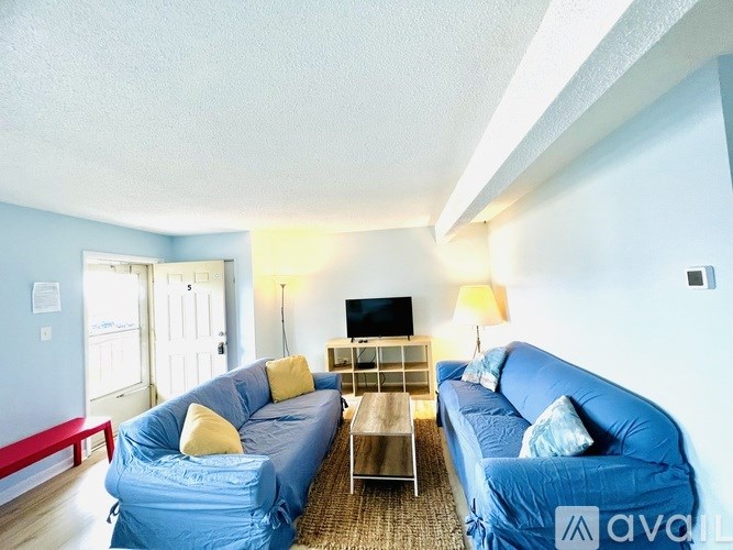 A living room with two blue couches and a television.
