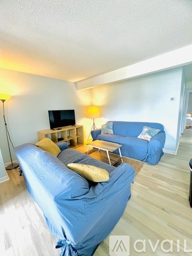 A living room with a blue couch and a television on a wooden stand.