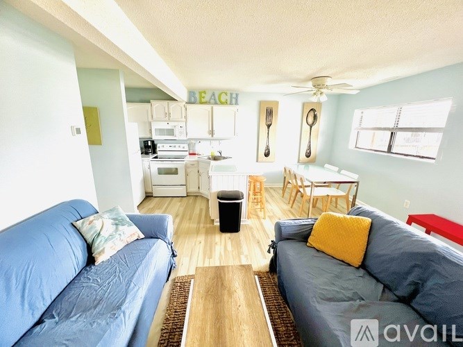A living room with a blue couch and a kitchen area in the background.
