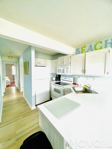 A kitchen with a white counter top and a sign that says "BEACH" on the wall.