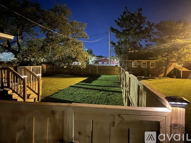 A backyard with a wooden fence and a green lawn.