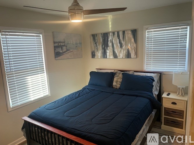 A bedroom with a blue bedspread and a ceiling fan.