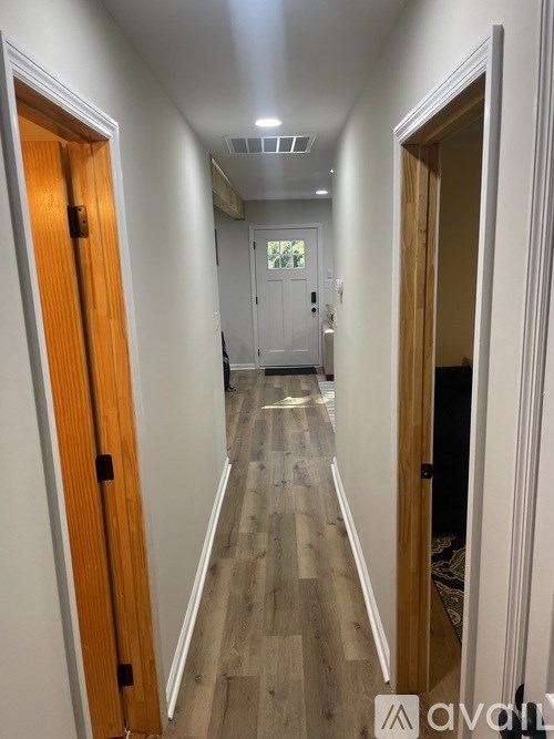 A long hallway with wooden floors and white walls.