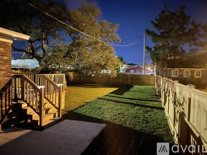 A backyard with a wooden deck and a green lawn.