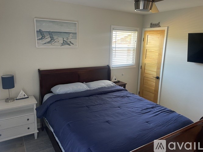 A bedroom with a bed, nightstand, and a painting on the wall.