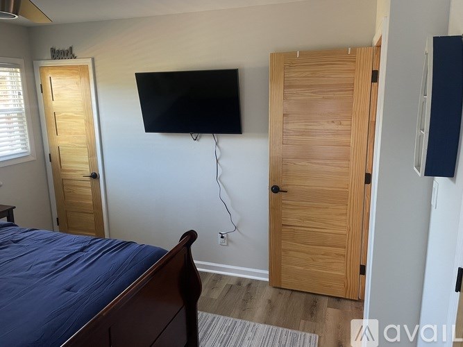 A bedroom with a bed, a flat screen TV, and a wardrobe.
