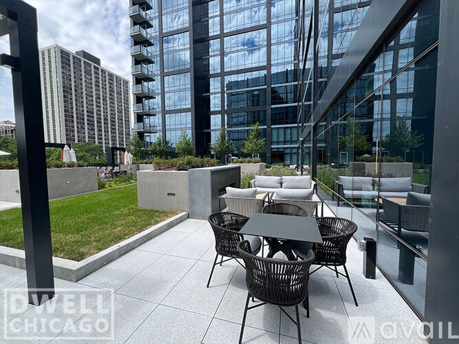 A patio with a table and chairs is in front of a glass building.