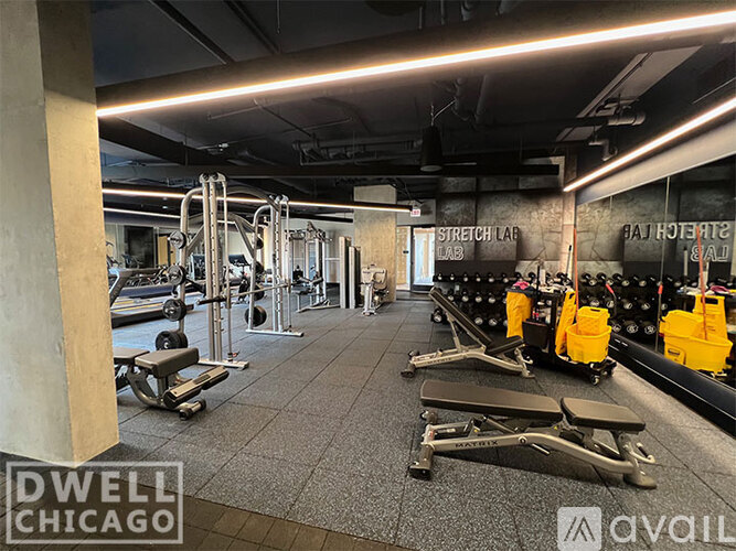 A gym with a variety of equipment including a rowing machine, a leg press machine, and a bench press.