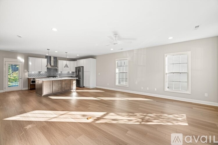 A spacious living room with a kitchen area in the background.
