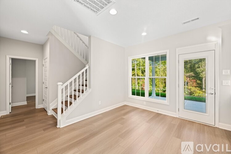A spacious room with a staircase and a view of the outdoors through the windows.