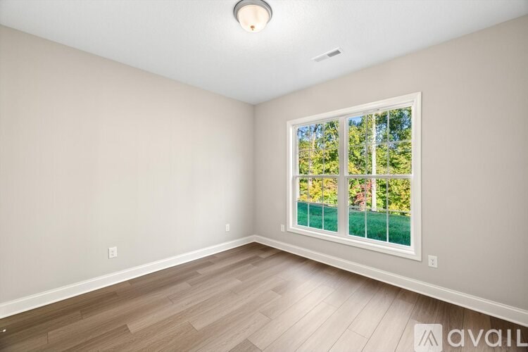 A room with a window that has a view of trees and a fence.
