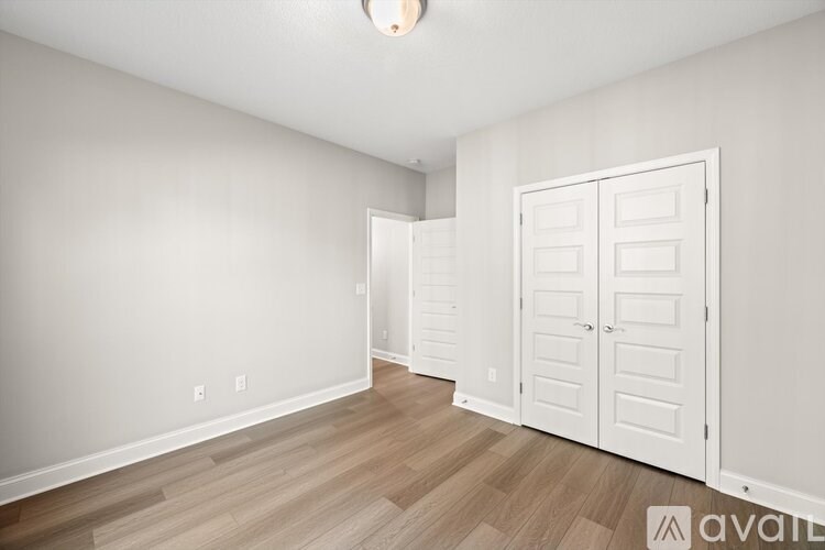 A room with a white door and wooden flooring.