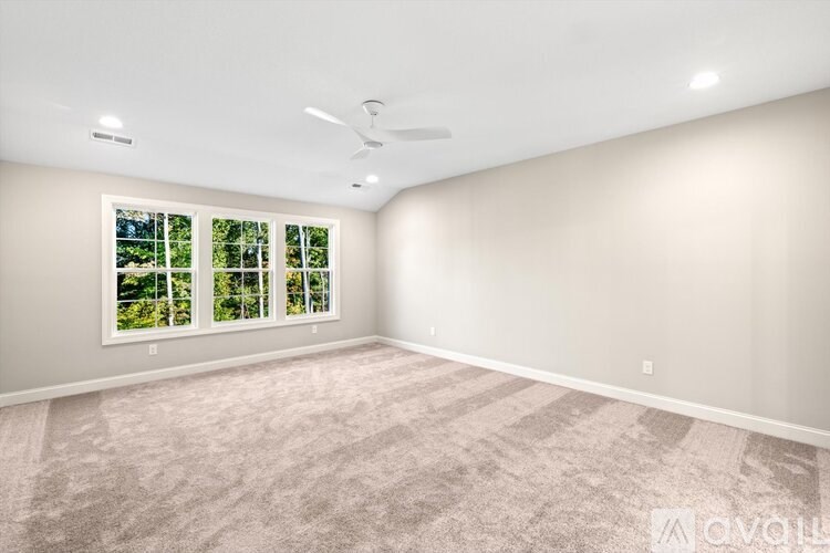 A spacious room with a carpeted floor and a ceiling fan.