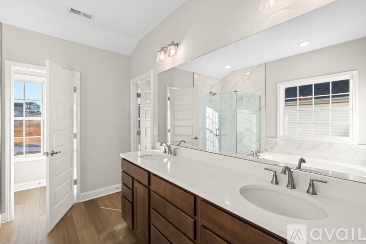 A bathroom with a large mirror, a sink, and a window with blinds.