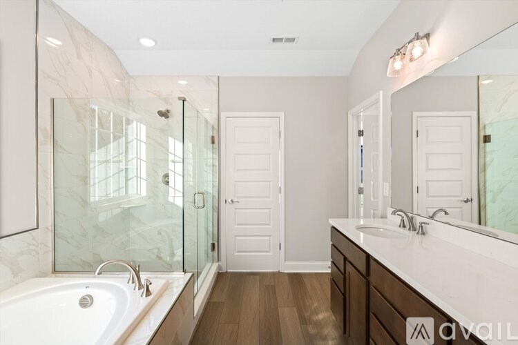 A bathroom with a tub, sink, mirror, and shower.