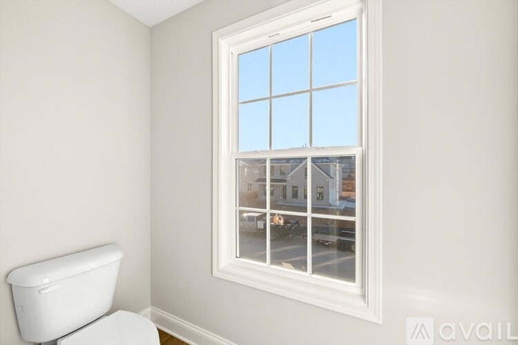 A white toilet sits next to a window in a room.