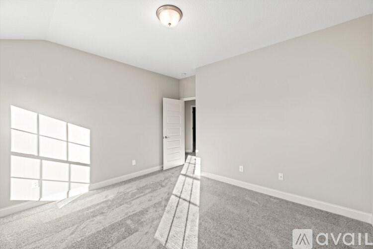 A room with a carpeted floor and a door on the right side.