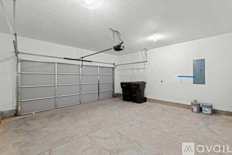 A spacious garage with a black trash bin and two buckets on the floor.