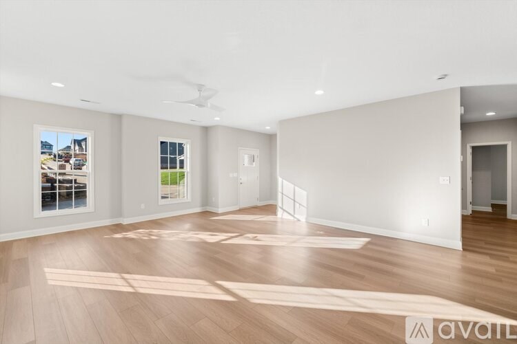 A spacious room with wooden floors and a ceiling fan.