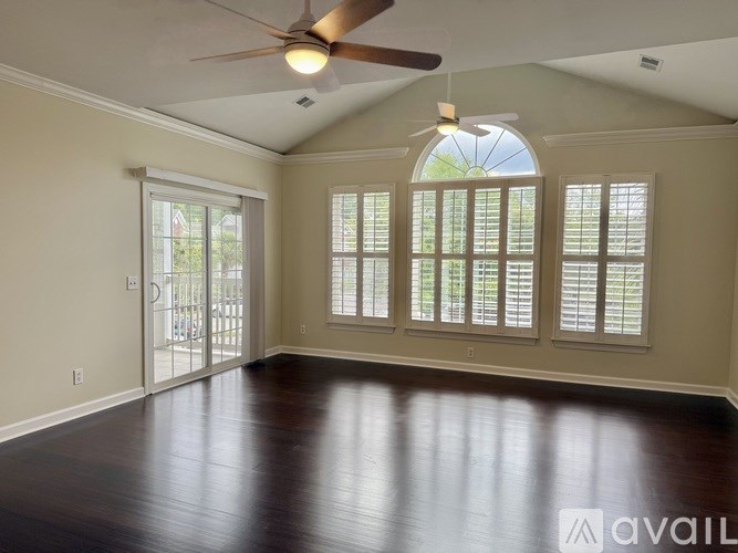 A room with a ceiling fan and sliding glass doors.
