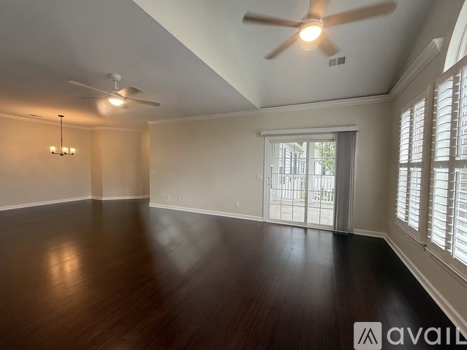 A spacious room with wooden floors and a ceiling fan.