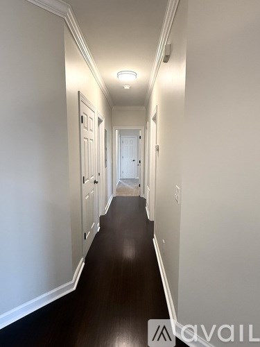 A long hallway with white walls and wood floors.