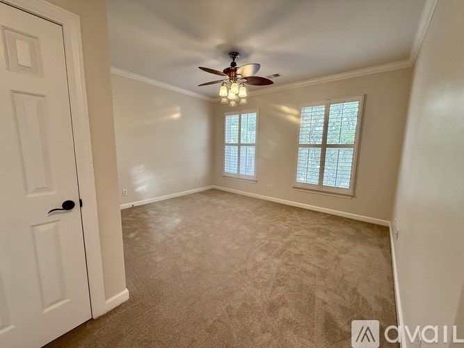 A room with a ceiling fan and two windows.